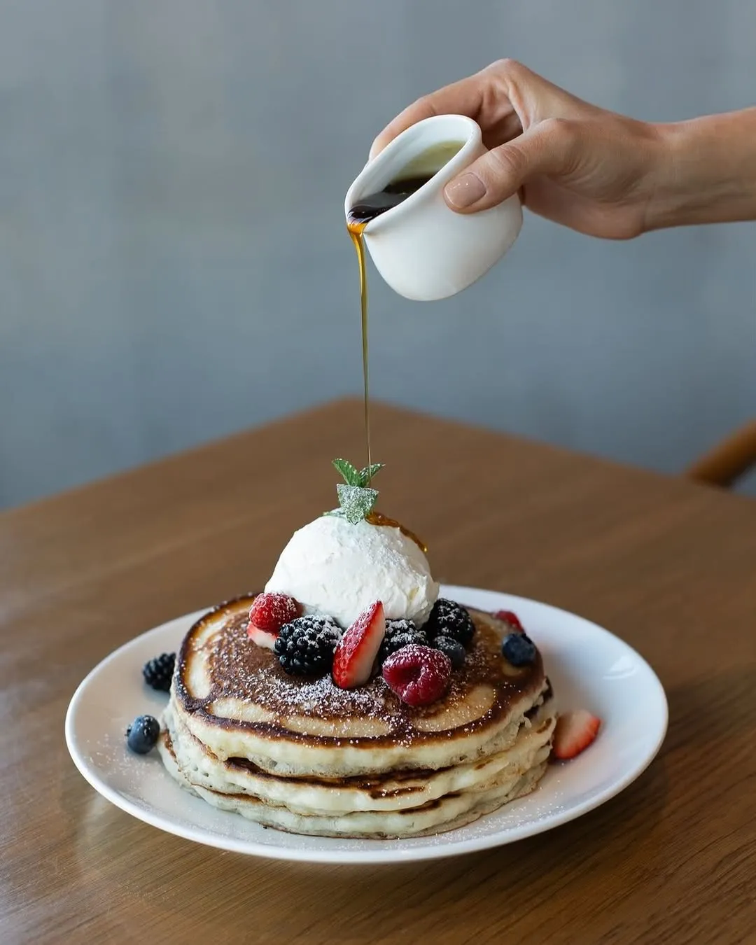 Pancakes with berries and a syrup pour