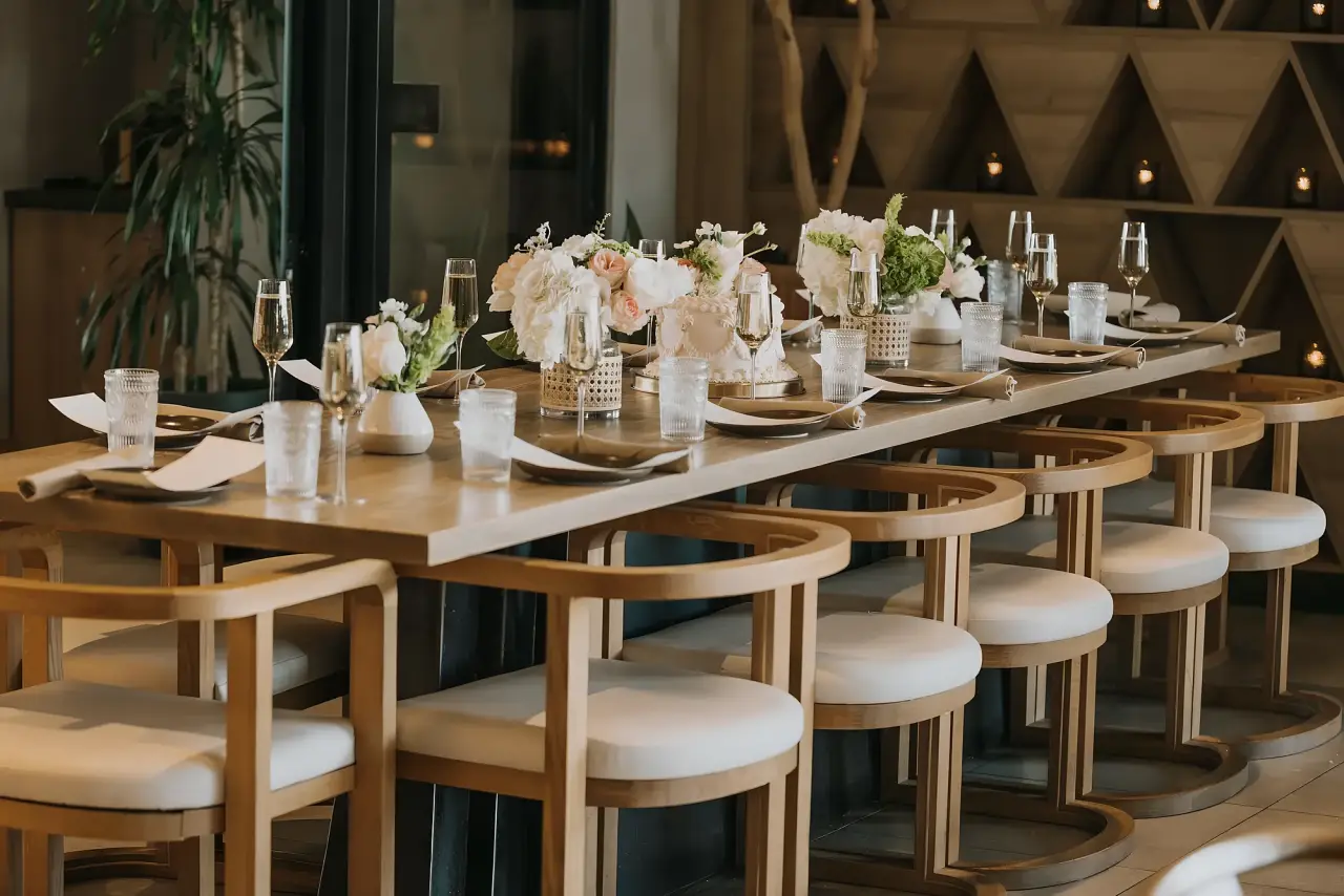 A long table with white florals set for a wedding